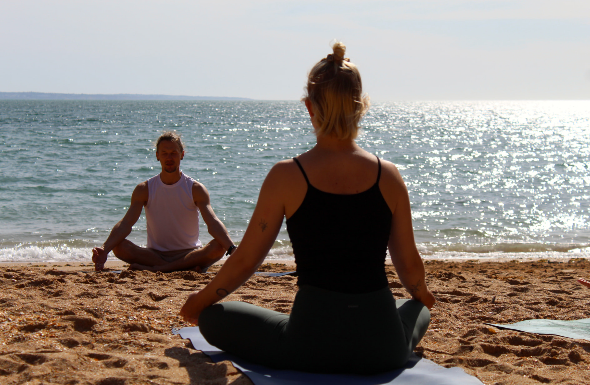 Private yoga class on a beach in Lagos, Algarve, with a yoga teacher and student meditating by the ocean.